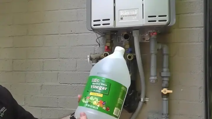 Wall-mounted tankless water heater with a jug of vinegar ready for a descaling flush