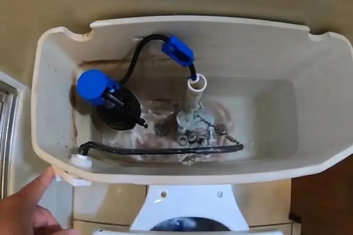 Open toilet tank showing the fill valve and flapper assembly