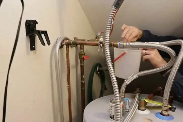 Technician working on the supply connections at the top of a residential water heater tank